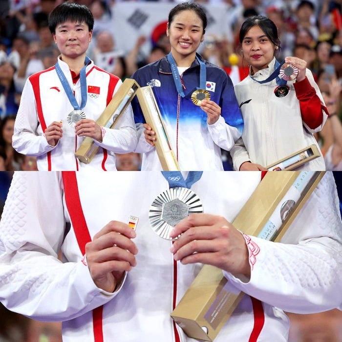 Chinese shuttler He Bingjiao carries Spanish flag badge onto the podium after her Spanish semifinal opponent's withdrawal due to injury