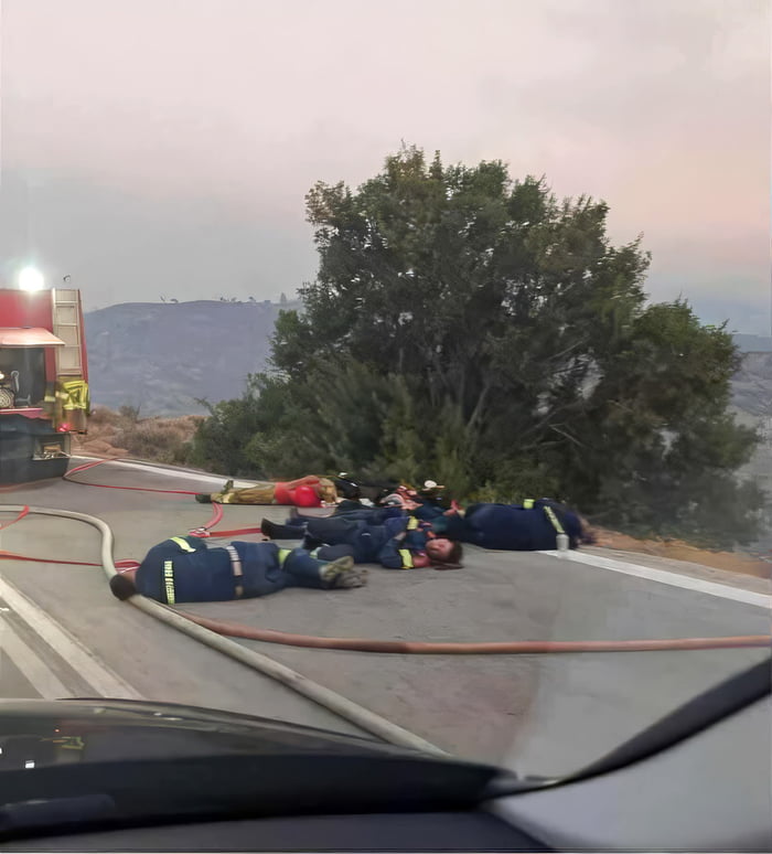 Romanian firefighters rest on the road after a 48-hour battle with the fires in Greece.