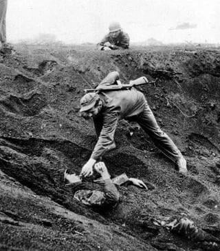 Marine giving a Japanese Soldier a cigarette after discovering he had buried himself and played dead for nearly two days, Iwo Jima, 1945